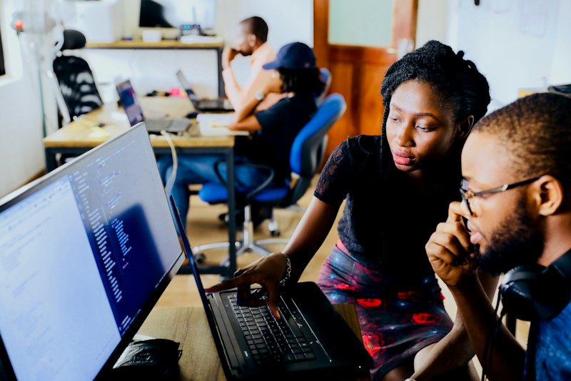Software engineers collaborating on code and custom systems development on monitor
